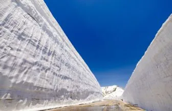 富山県 立山黒部アルペンルート 室堂・雪の大谷の巨大な雪の壁と青空